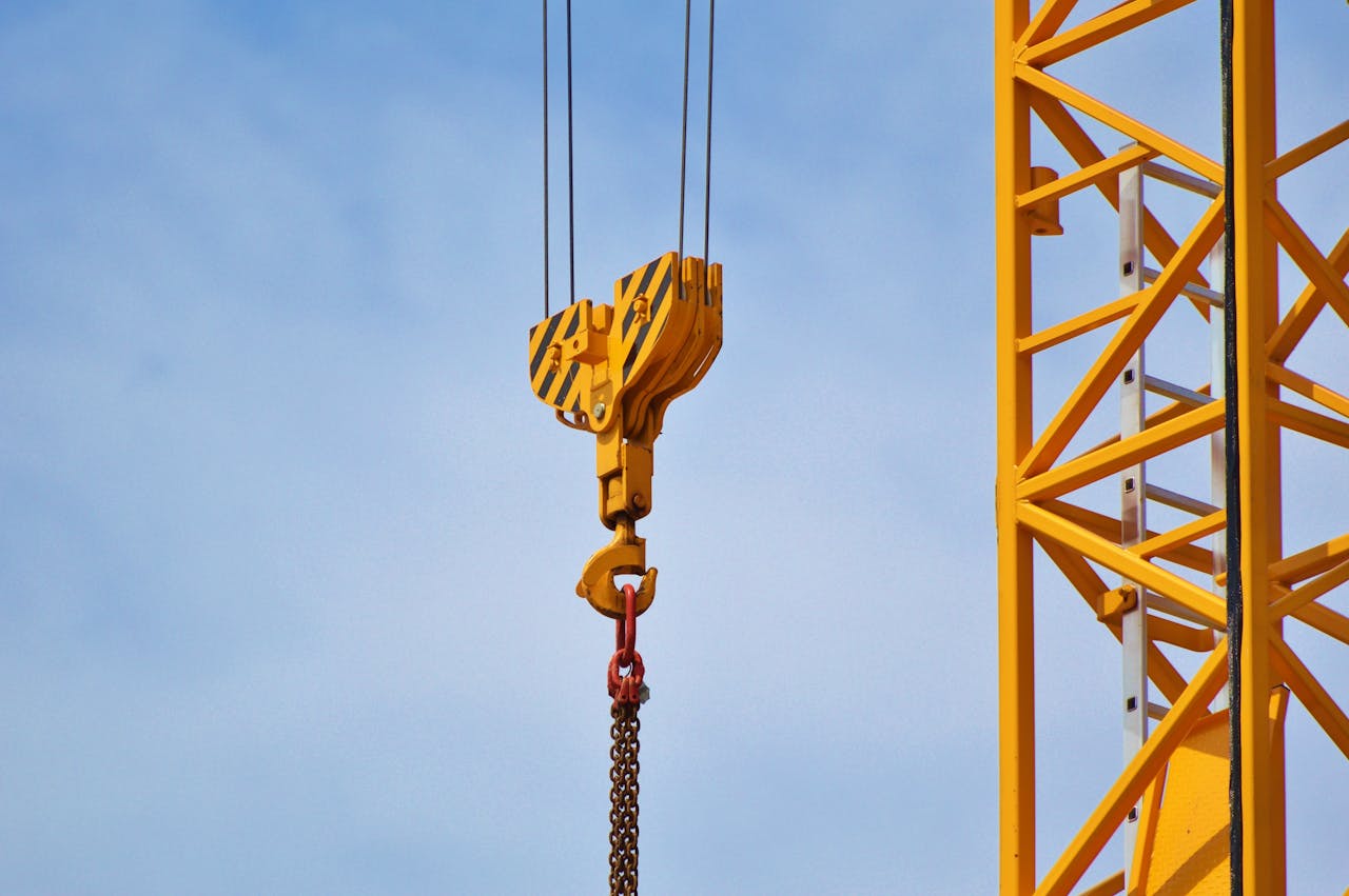 الرئيسية Close-up of a yellow crane arm against a clear blue sky, showcasing industrial equipment.